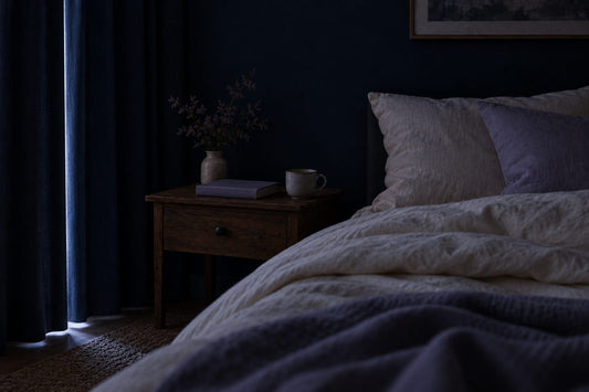 Chambre dans le noir, rideaux occultants bleu nuit tirés, un mince filet de lumière au bord